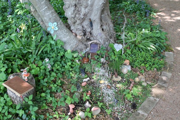 A fairy garden at the base of a tree.